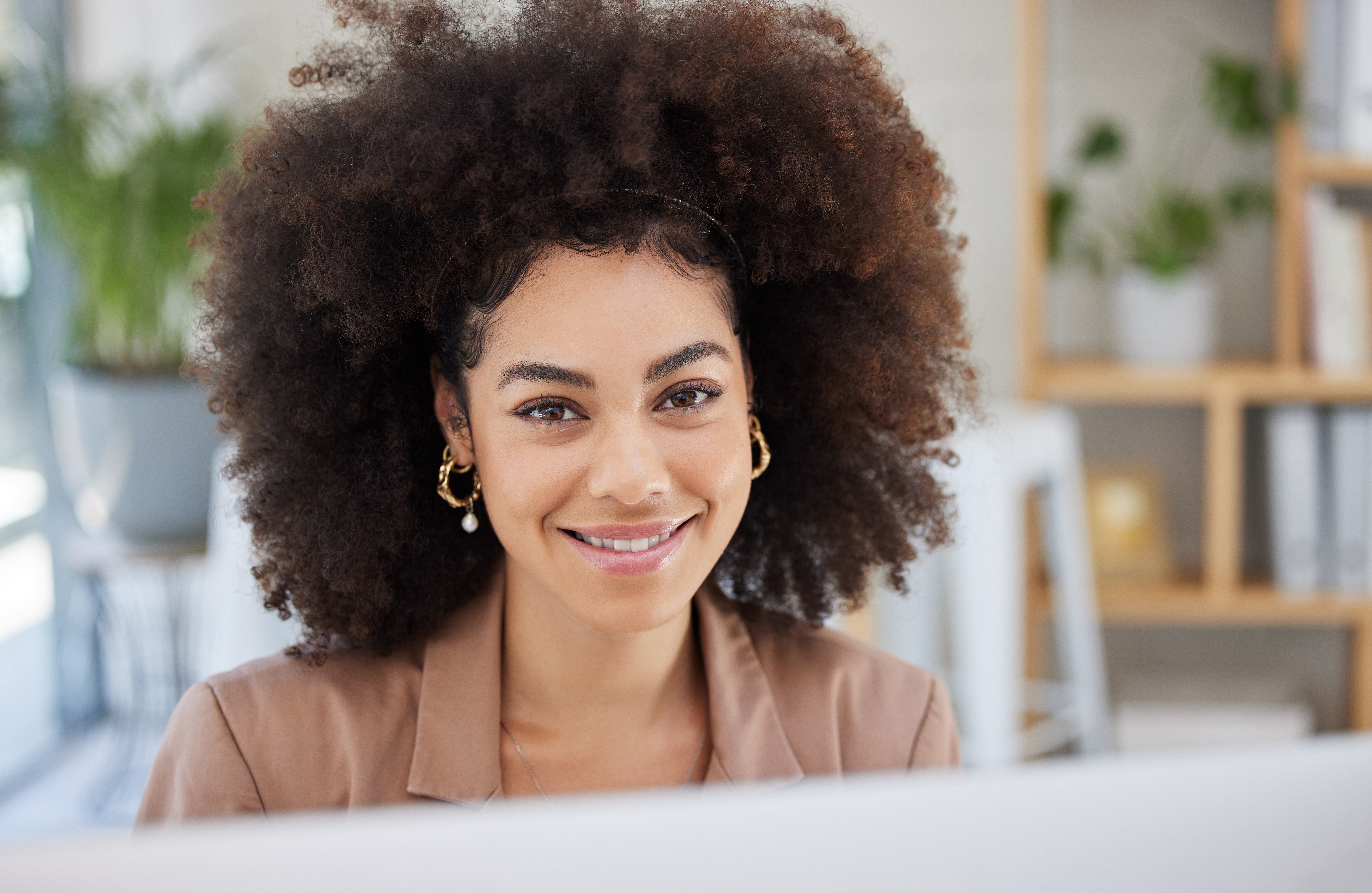 Closeup portrait of one young smiling African American woman using a desktop while sitting at a des.
