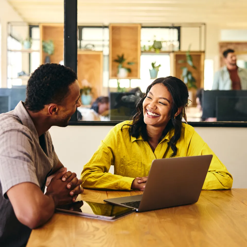 man and woman smiling in front of laptop