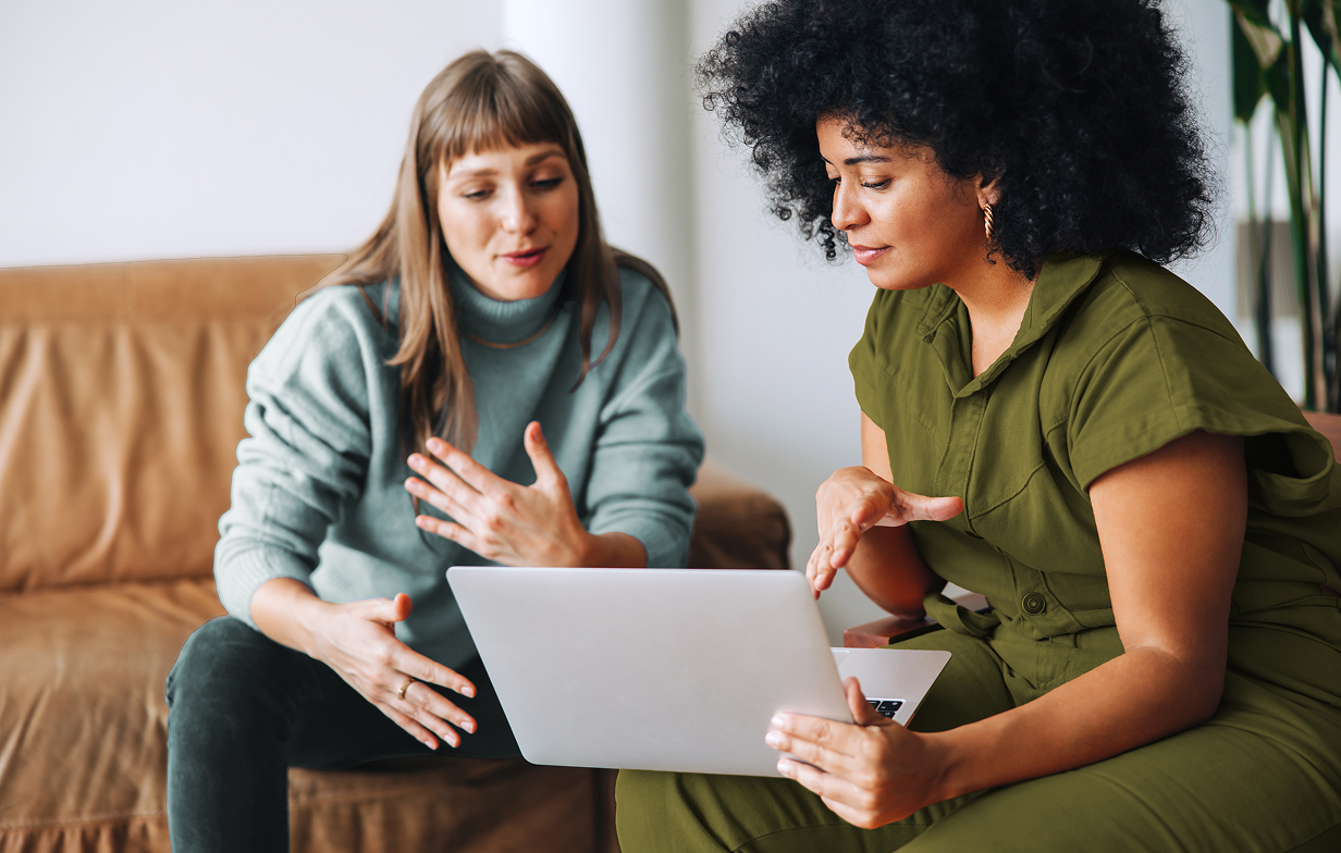 two women sitting looking at a laptop screen