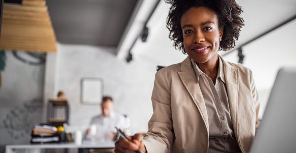 Business person, looking at camera, colleague in the background.