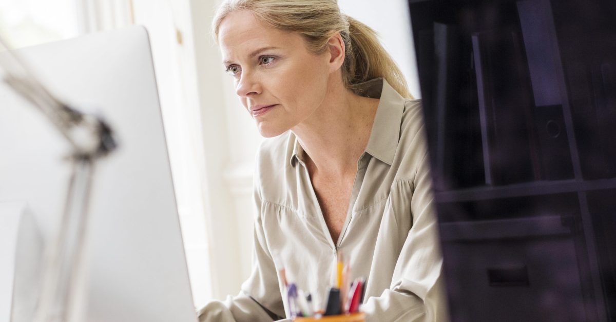 Female designer typing at desktop computer in creative studio
