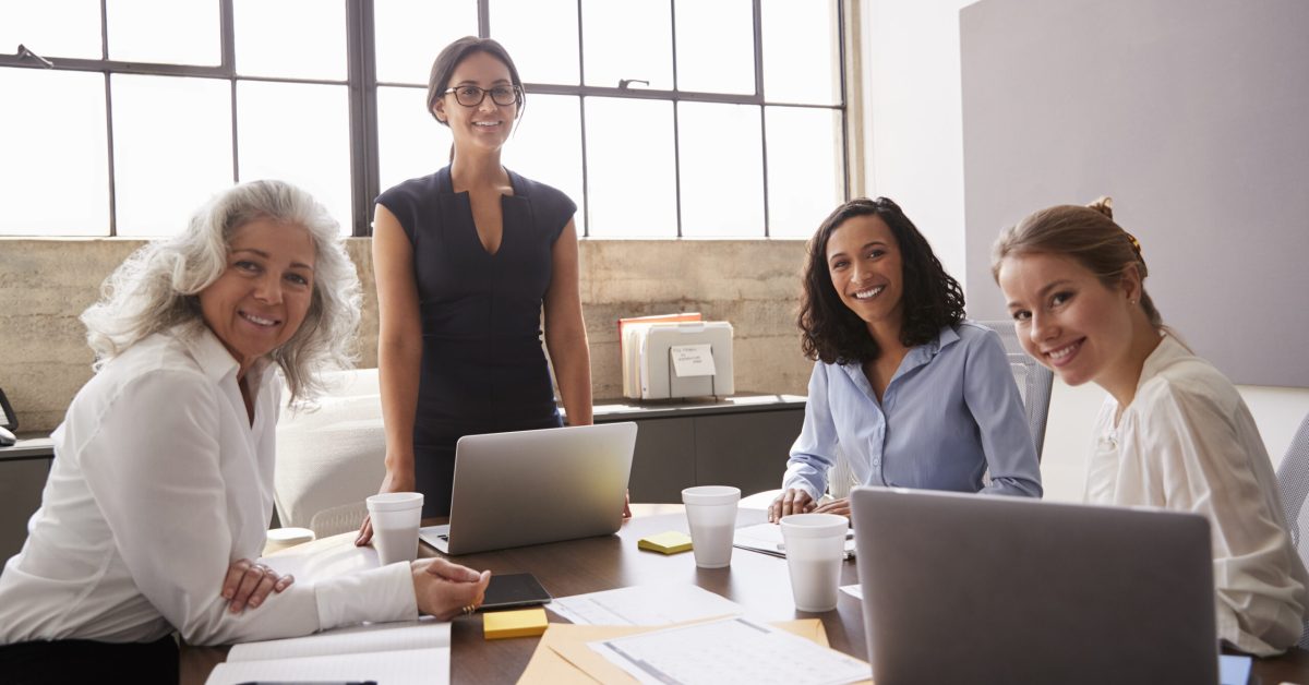 Four marketers working together at a table, looking to camera/