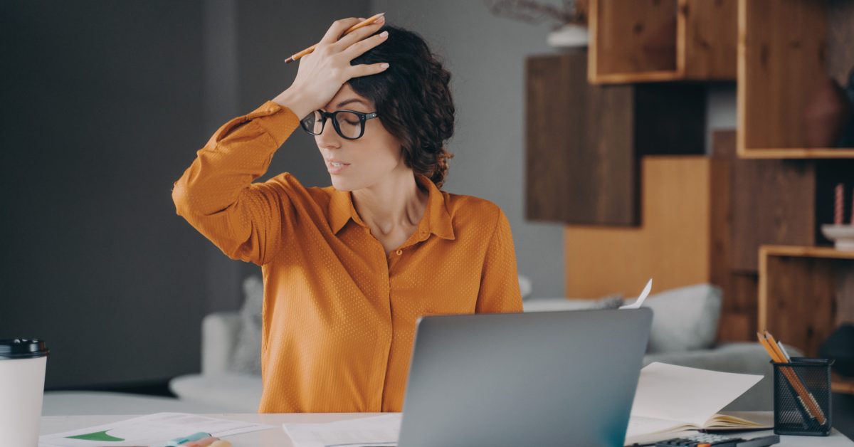 Frustrated Italian female employee stressed about mistake or problem with computer, got bad news from office. Tired nervous spanish woman working remotely online from home. Pressure at work concept