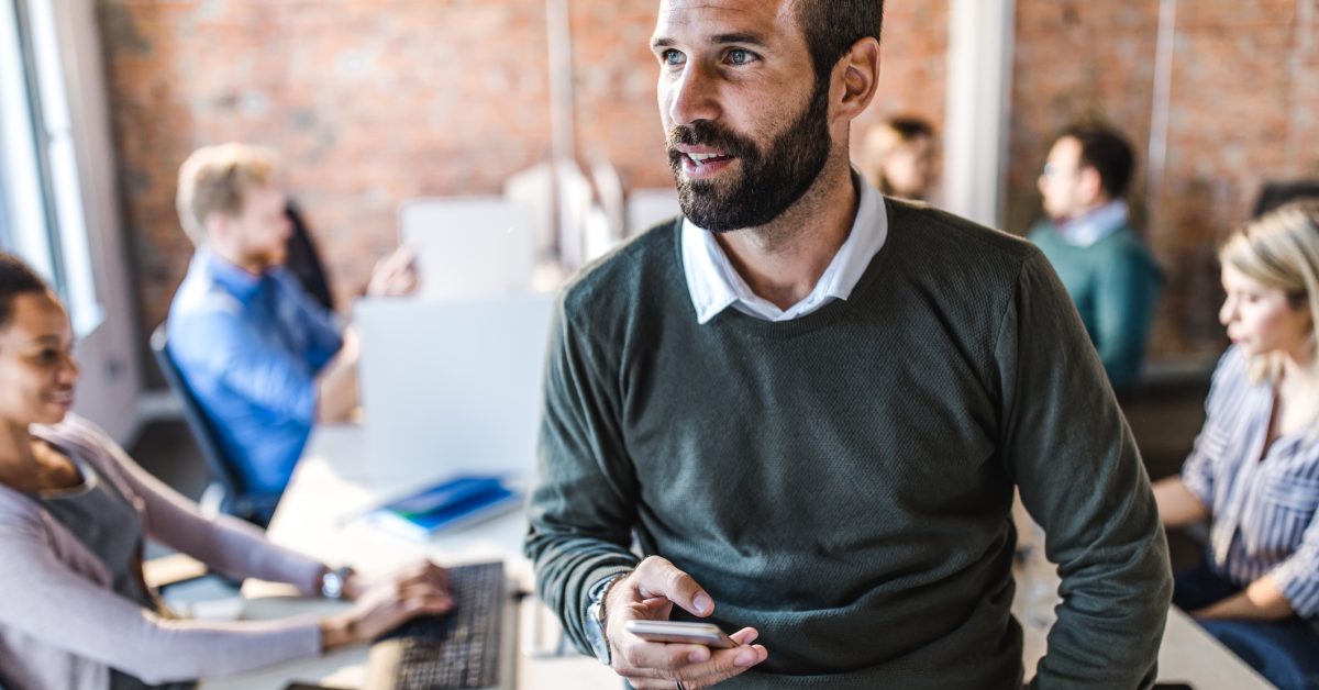 Marketing leader looking away from table where his team is working