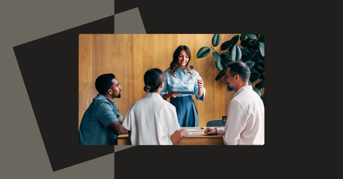 Group of people in an office having a meeting with three seated and one standing