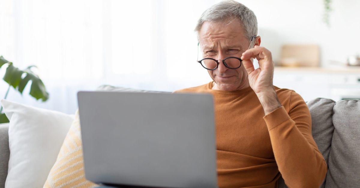 Man squinting at a laptop screen