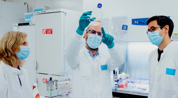 scientists in a lab looking at a solution in a jar